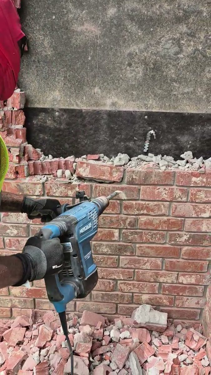 Crew member cutting into a brick wall with a rotary hammer